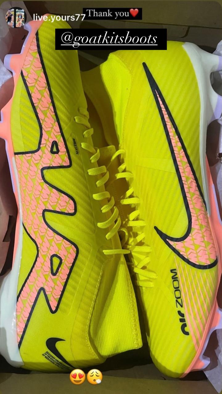 Bright yellow Nike Zoom football boots with pink accents displayed in their box, tagged with @goatkitsboots and emojis expressing love and excitement, highlighting vibrant sports footwear.